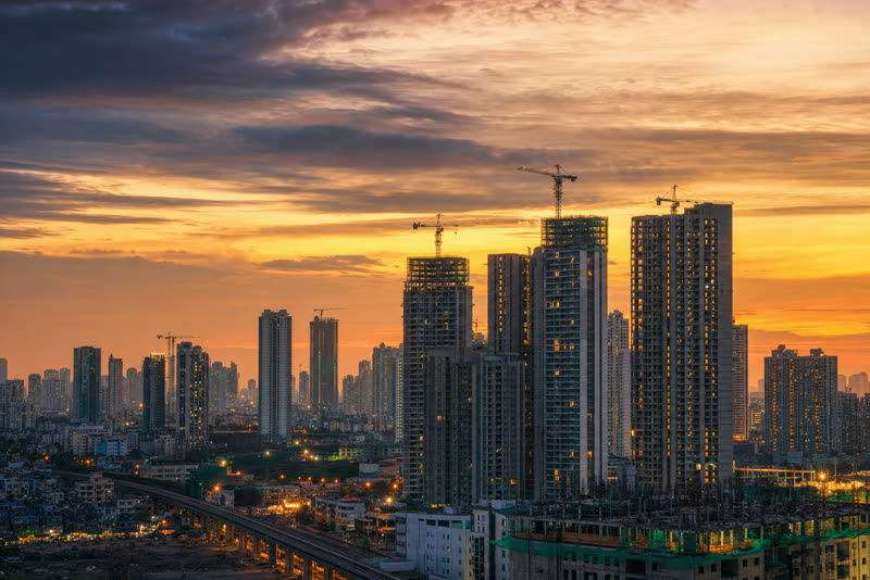 Growing city skyline with towers under construction at sunset